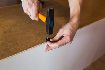 man hammers a nail, man hands assembling furniture