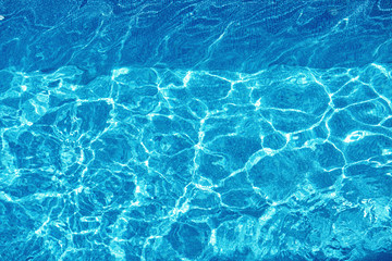 Fototapeta na wymiar Water Background. Shining Blue Ripped Water Surface In Hotel Swimming Pool With Bright Sunny, Sun Light Reflections. Liquid Texture. Summertime. Summer Holidays Vacation Concept.