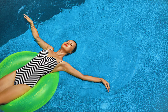 Summer Vacations. Beautiful Sexy Smiling Woman With Perfect Fit Body, Healthy Skin In Swimwear Sunbathing, Floating On Float Swim Ring In Swimming Pool Water. Enjoyment. Beauty, Wellness. Recreation