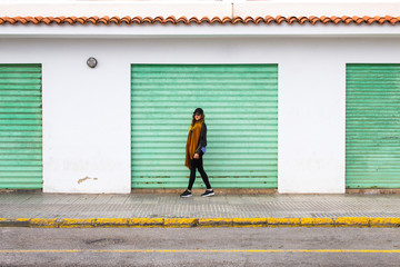 Young girl standing against coloured industrial wall with garages
