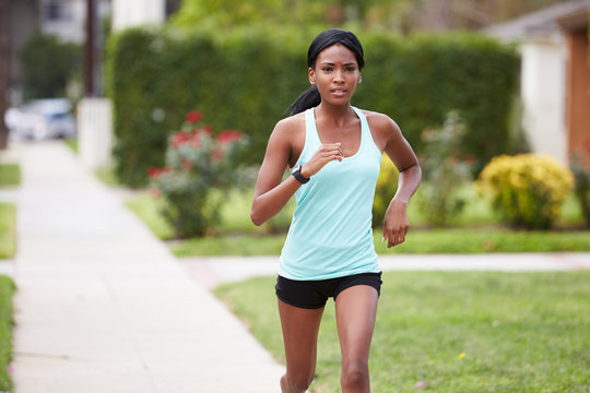 Young black woman in sports clothes running in the street