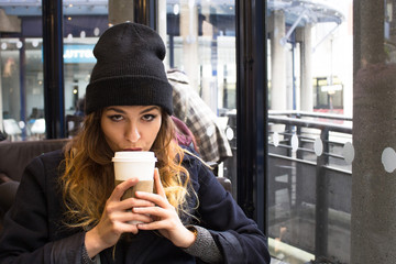 Young attractive girl drinking coffee from a paper cup
