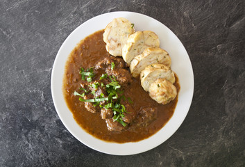Czech traditional recipe for beef goulash with homemade dumpligs, served in simple rustic style