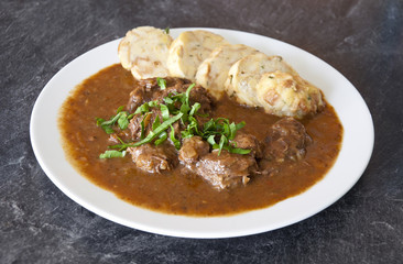 Czech traditional recipe for beef goulash with homemade dumpligs, served in simple rustic style