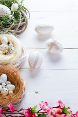 Fototapeta na wymiar Beautiful Easter background with flowers and nest with eggs on white painted boards