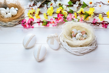 Beautiful Easter background with flowers and nest with eggs on white painted boards