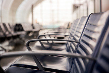 Row of  empty leather chairs in the departure lounge at the airport.  International airport terminal and the window background.