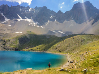 Hiker walking on the edge of lac Sainte Anne, Queyras, the Alps, France