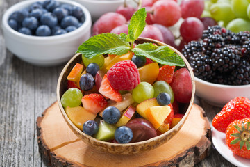 fruit salad in a bamboo bowl and fresh berries, close-up
