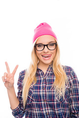 Obraz na płótnie Canvas Happy girl in cap and glasses gesturing with two fingers and sho