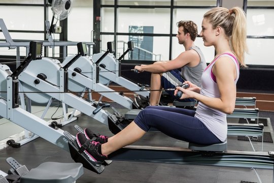 Man And Woman Working Out On Rowing Machine