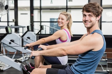 Fototapeta na wymiar Portrait of a man and woman working out on rowing machine