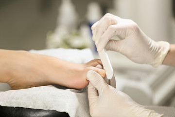 Obraz na płótnie Canvas Close-up pedicure process of the big toe in spa salon. Professional work pedicure masters.