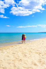 Fototapeta na wymiar Mother and daughter walking on the beach, tropical sea background