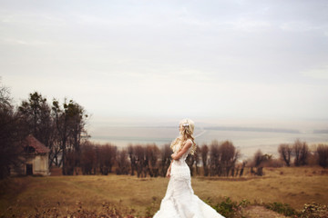 Fototapeta na wymiar cute blonde bride in lace dress posing smiling walking