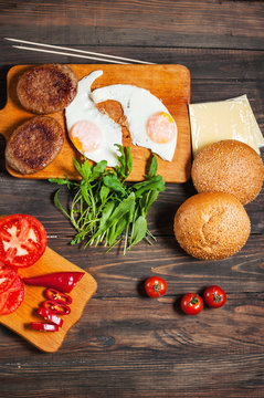 Ingredients for cheeseburgers on a dark wooden background