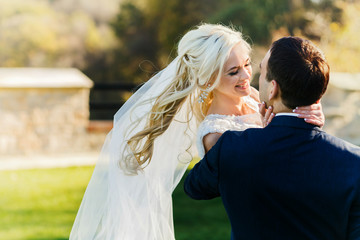 rich groom and bride holding hands outdoor background wall grass