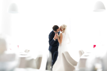 blonde bride and brunette groom in resturant near white windiw