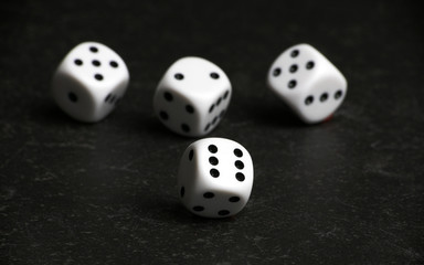 Four white and black dice on a black table