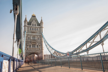 Fototapeta na wymiar Long exposure of pedestrians crossing Tower Bridge. People have been blurred to a ghostly shape.