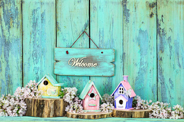 Welcome sign hanging over birdhouses on cedar logs