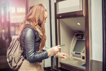 Young woman withdrawing money from credit card at ATM - obrazy, fototapety, plakaty