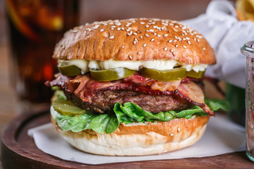 Close up on fresh burger in bun with sesame with lettuce, tomato, beef and bacon.