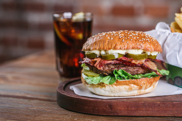 Fresh burger in bun with sesame with lettuce, tomato, beef and bacon.