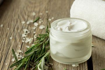 Face cream and rosemary on wooden table