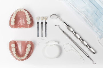 Dentures next to floss and metal pick and mirror