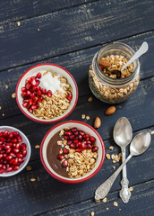 Healthy Breakfast - yogurt with homemade granola and pomegranate on a dark wooden board