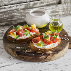Tomato and cheese bruschetta on a rustic wooden cutting board. Healthy breakfast, snack or appetizer with wine