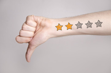 Mans hand showing thumb down and two star rating tattoo like drawing
