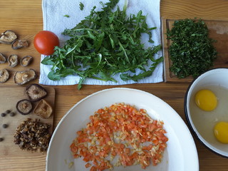 Cooking dandelion leaves omelette with mushrooms shiitake, tomato and onion