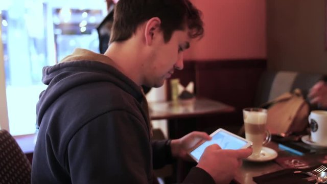 Young man using tablet computer in cafe