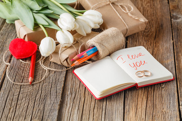 Fototapeta premium I love you phrase in notebook with flowers on table