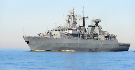 Grey modern warship sailing in still water