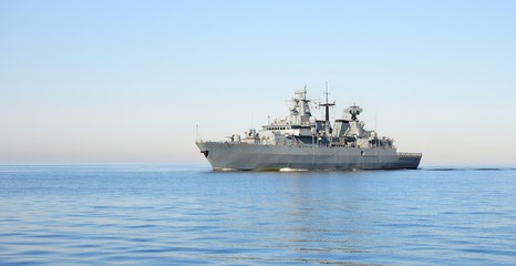Grey modern warship sailing in still water