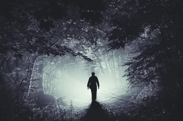 Foto op Plexiglas surrealistisch licht in donker bos en man silhouet © andreiuc88