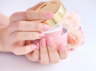 Hands of a woman with pink manicure with cream