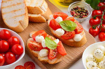 Bruschetta with cherry tomatoes and mozzarella on wooden board.