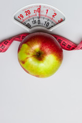 Apple with measuring tape on weight scale. Dieting