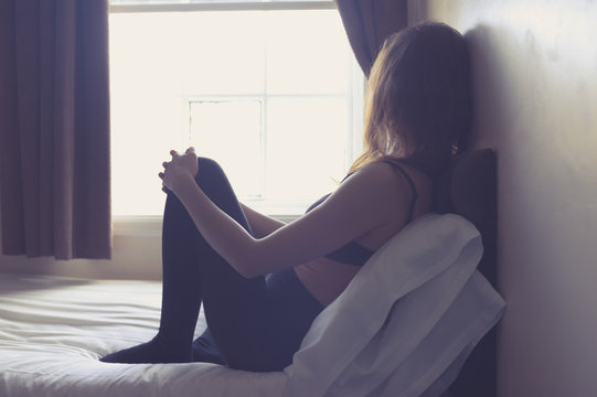 Young woman sitting on bed in the morning
