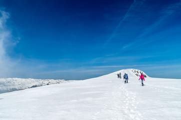 Fototapeta na wymiar Winter landscape in the mountains. Group of hikers. Mountain ridges covered by snow in winter in Europe.