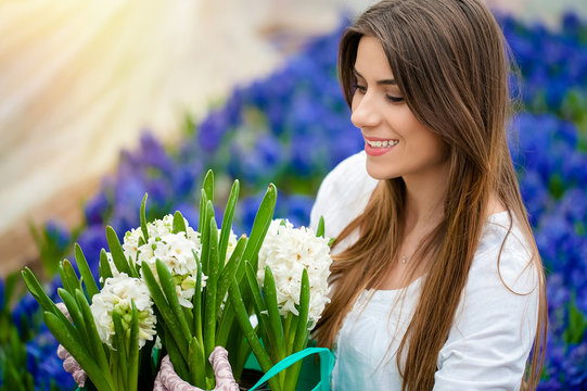 Young beautiful woman holding a pot with white hyacinth flower in a greenhouse.