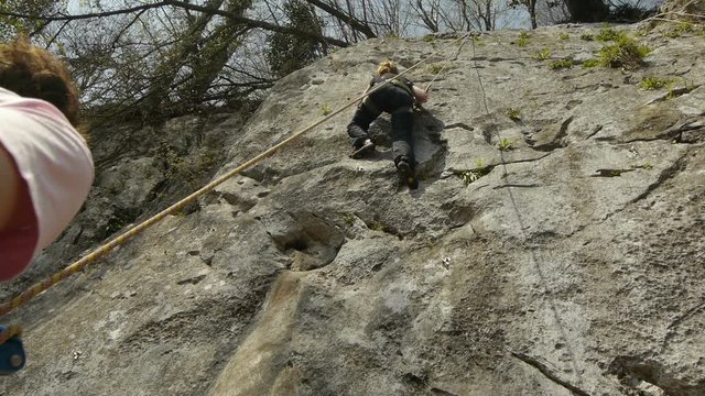 Low angle view of female climber slip, falling down a rock wall.
