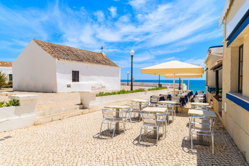 Church and restaurant  on coastal promenade in seaside town of Armacao de Pera, Portugal