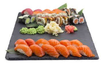 Japanese cuisine. Salmon sushi nigiri and rolls on a black stone plate isolated on white background