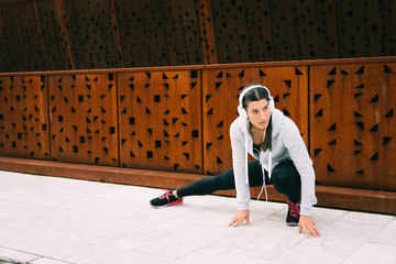 Young female athlete stretching adductors for cooling down after urban running or outdoor fitness workout. Young woman training and exercising outside.