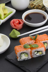 Sushi roll with fresh ingredients with ginger wasabi over black background